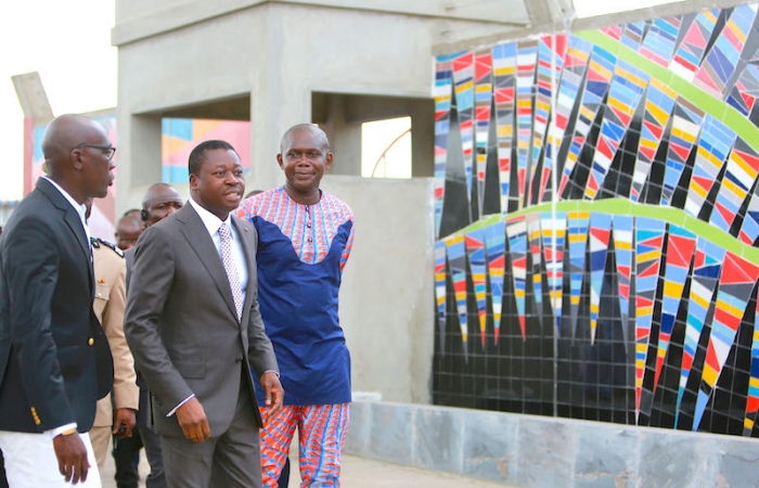 L'artiste Emmanuel Sogbadji auteur de la fresque -La paix t'accueille- expliquant son oeuvre au chef de l'État